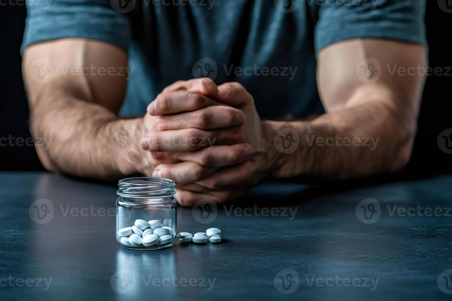 Patient suffering from painkiller addiction is clasping hands in front of pill bottle photo