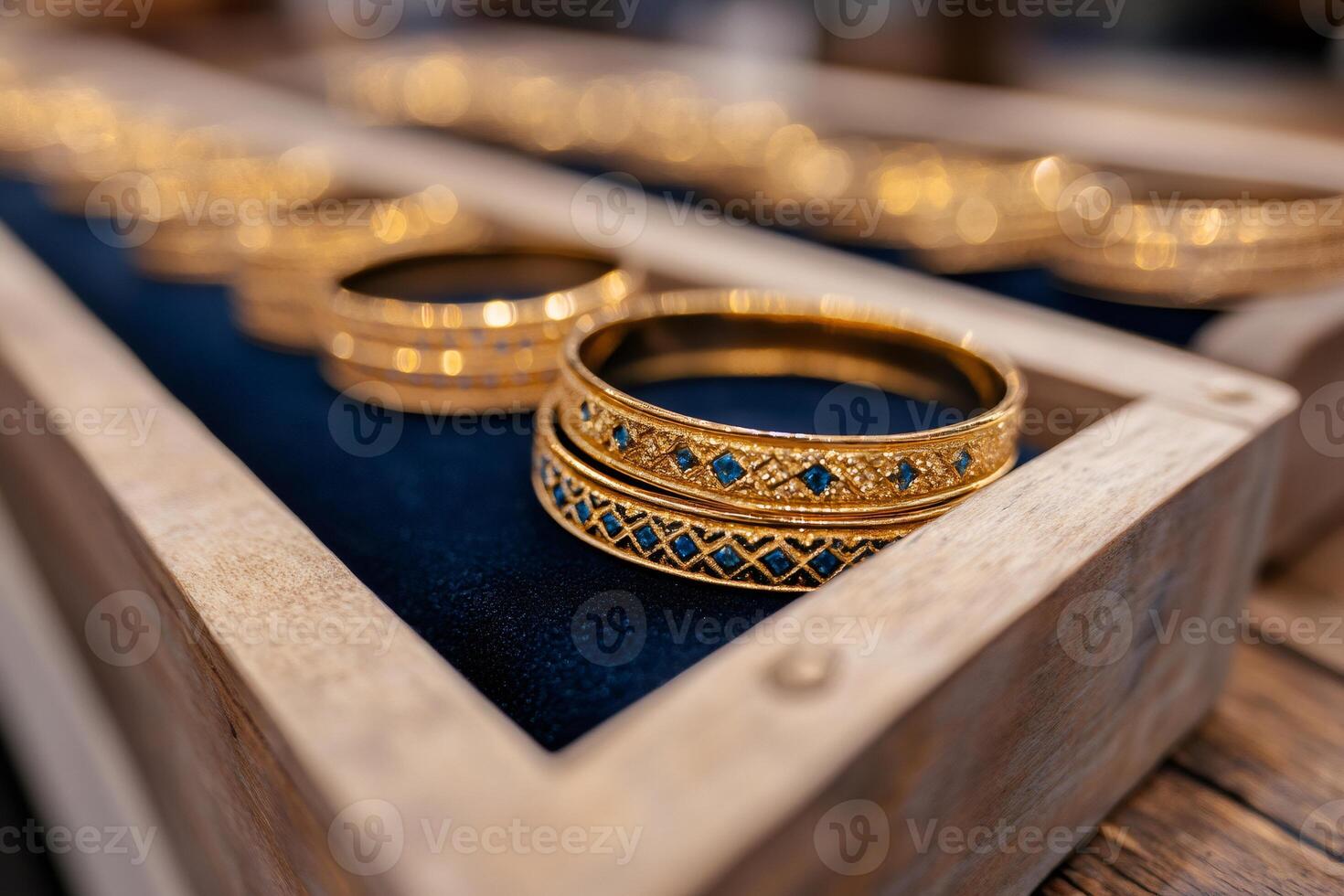 Golden bracelets with blue gems resting on dark blue velvet in wooden box photo