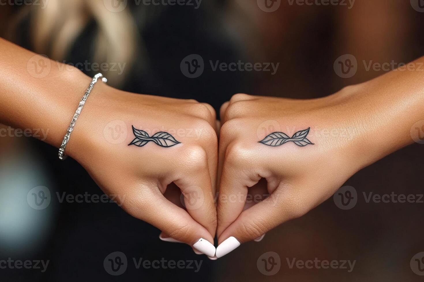 Two hands showing matching minimalist leaf tattoos photo