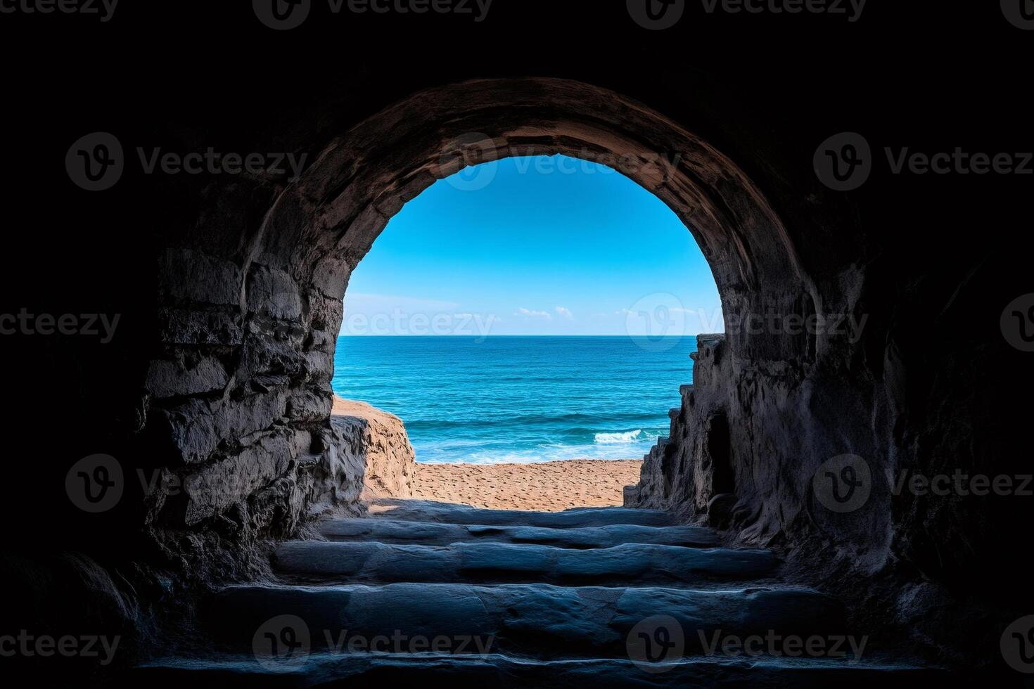Stone archway opening onto sunny beach and blue ocean photo