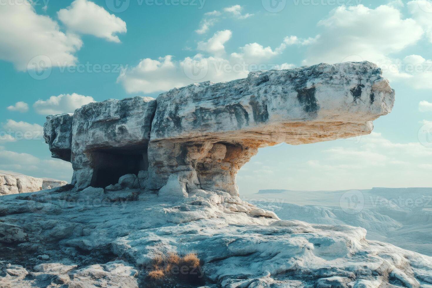 Large overhanging rock formation dominating the arid landscape under a cloudy sky photo