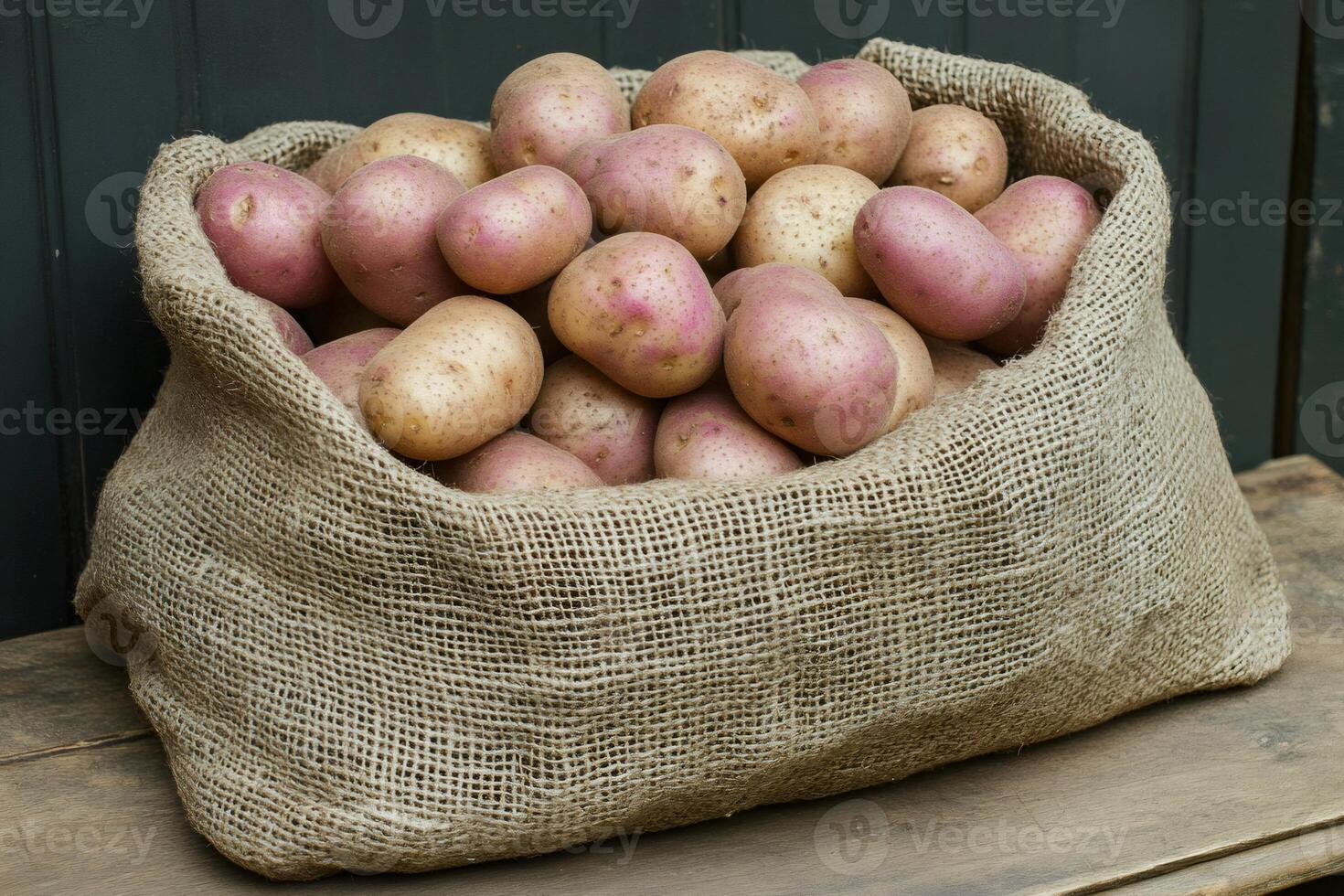 Burlap sack overflowing with freshly harvested potatoes on rustic wooden surface photo
