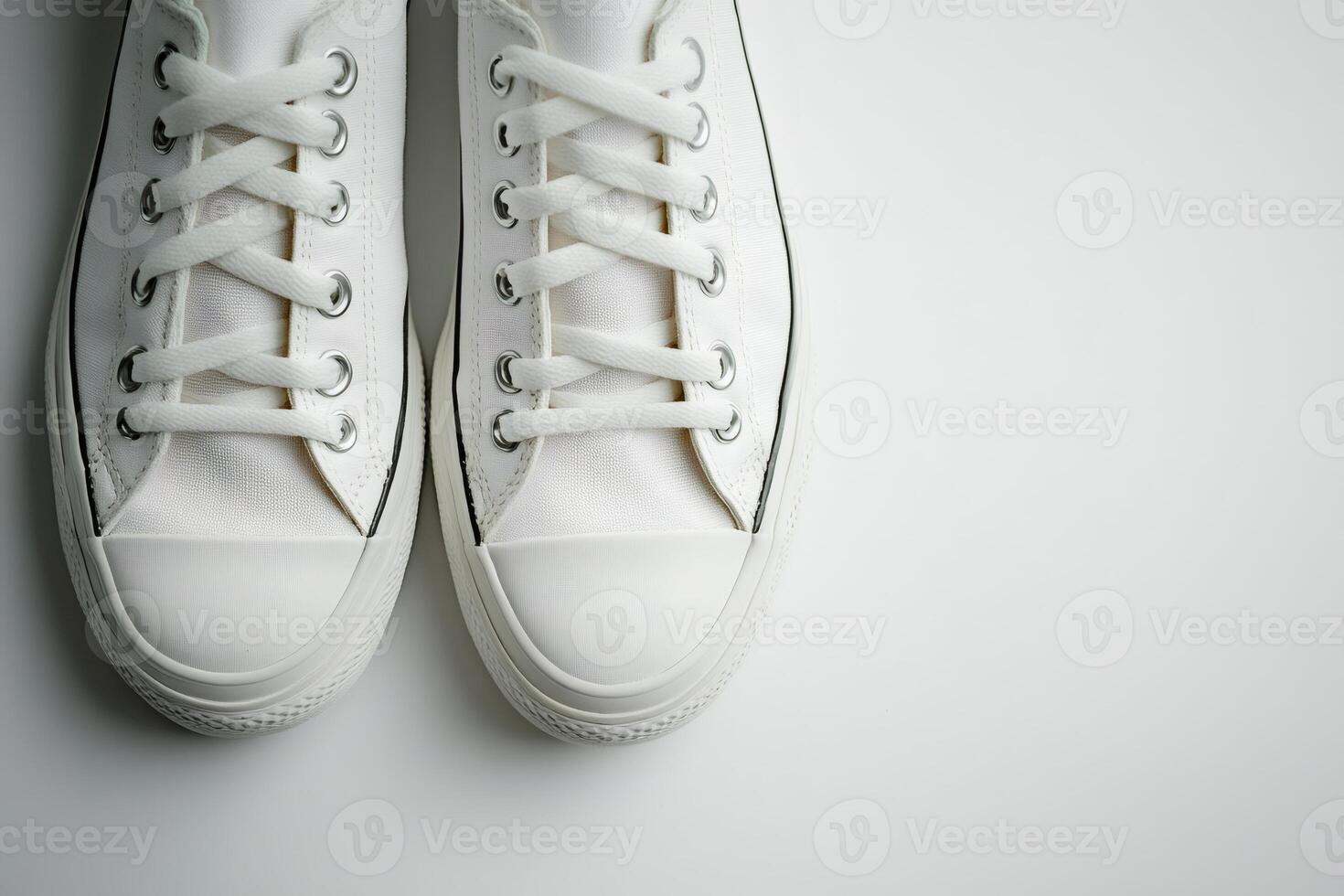 Pair of white canvas sneakers resting on white background photo