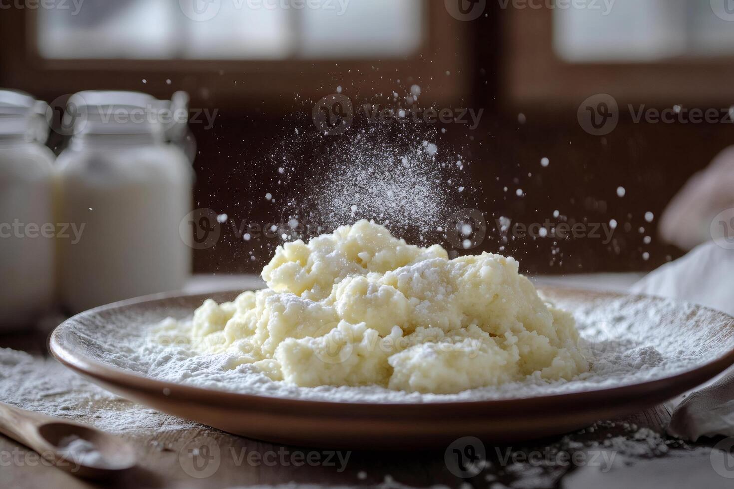 Sprinkling icing sugar on fresh homemade quark dumplings with milk in background photo