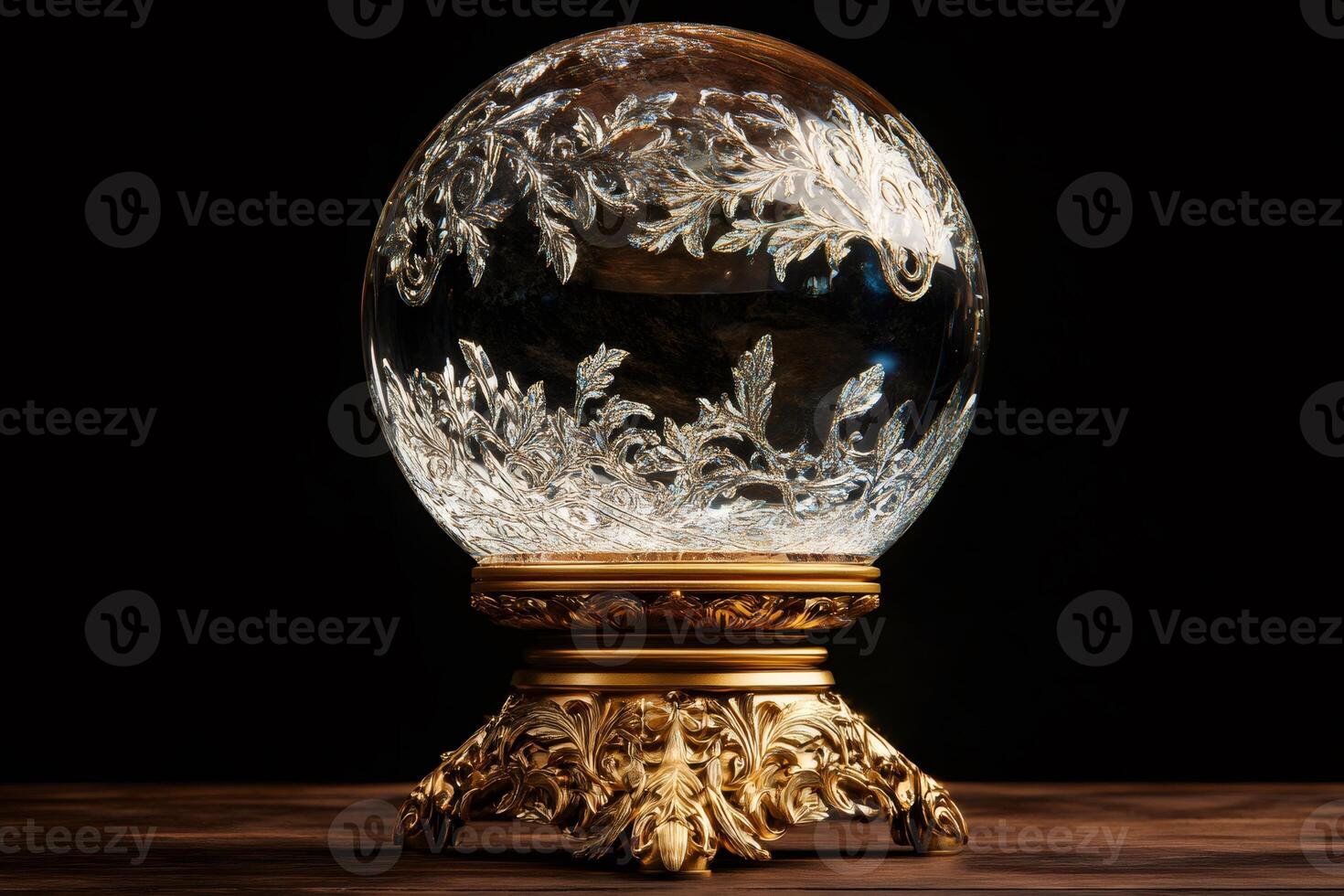 Crystal Ball with Etched Foliage on Ornate Gold Stand Displayed on Wooden Surface photo
