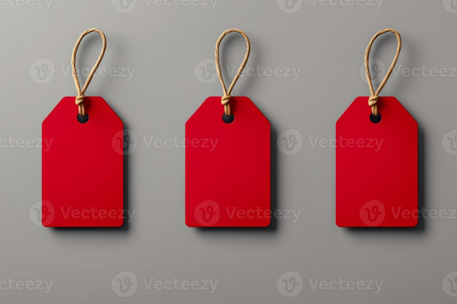 Three red blank hanging price tags with string on gray background photo