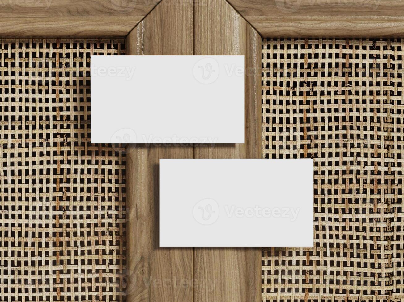 Mockup of two business cards placed on a natural rattan background with a clean wood frame for a minimalist design. photo