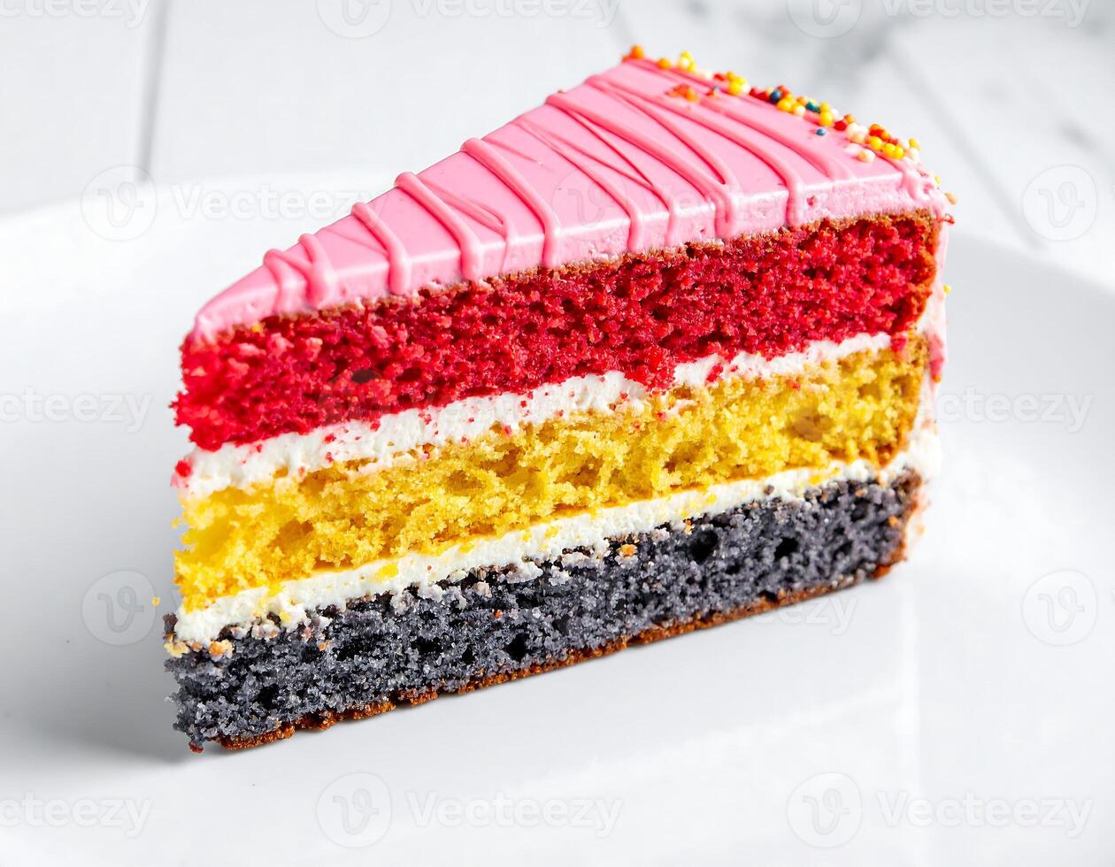 Slice of colorful layer cake with pink icing and sprinkles sitting on white plate photo
