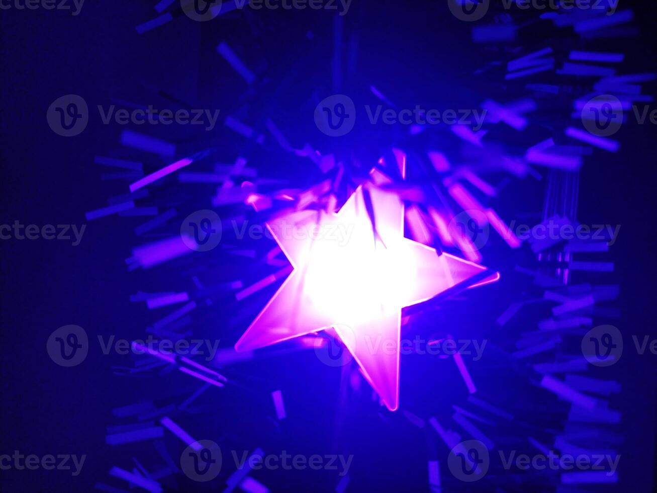 Glowing pink star surrounded by blue confetti. Vibrant, abstract image perfect for backgrounds, holiday designs, or music projects. Evokes feelings of celebration and energy. photo