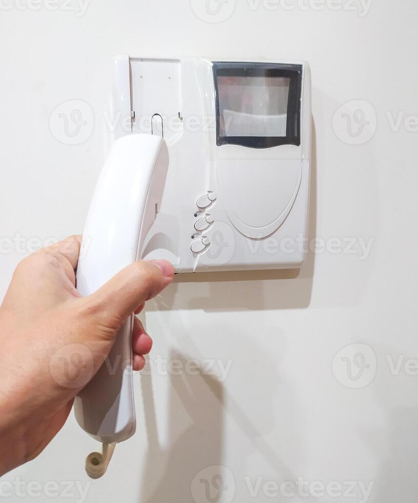Hand holding intercom phone, security concept. Calling for assistance, receiving visitors. Use for home safety, building access, communication themes. photo