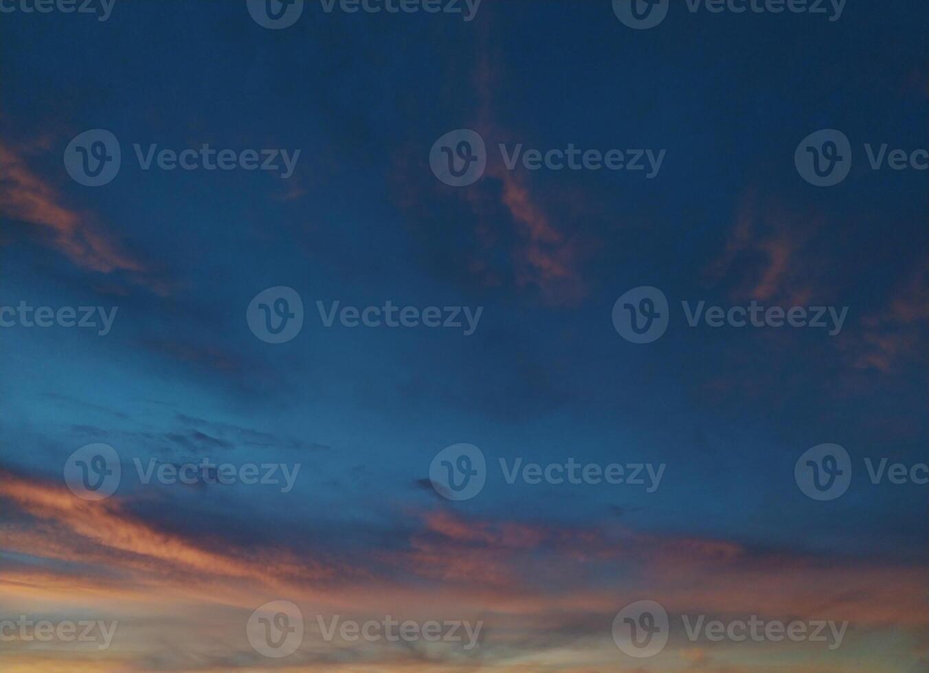 Stunning twilight sky, painted with soft peach and rose hues against a deep blue canvas. Silhouetted trees at the bottom add a touch of nature. Ideal for travel, nature, or serenitythemed projects. photo