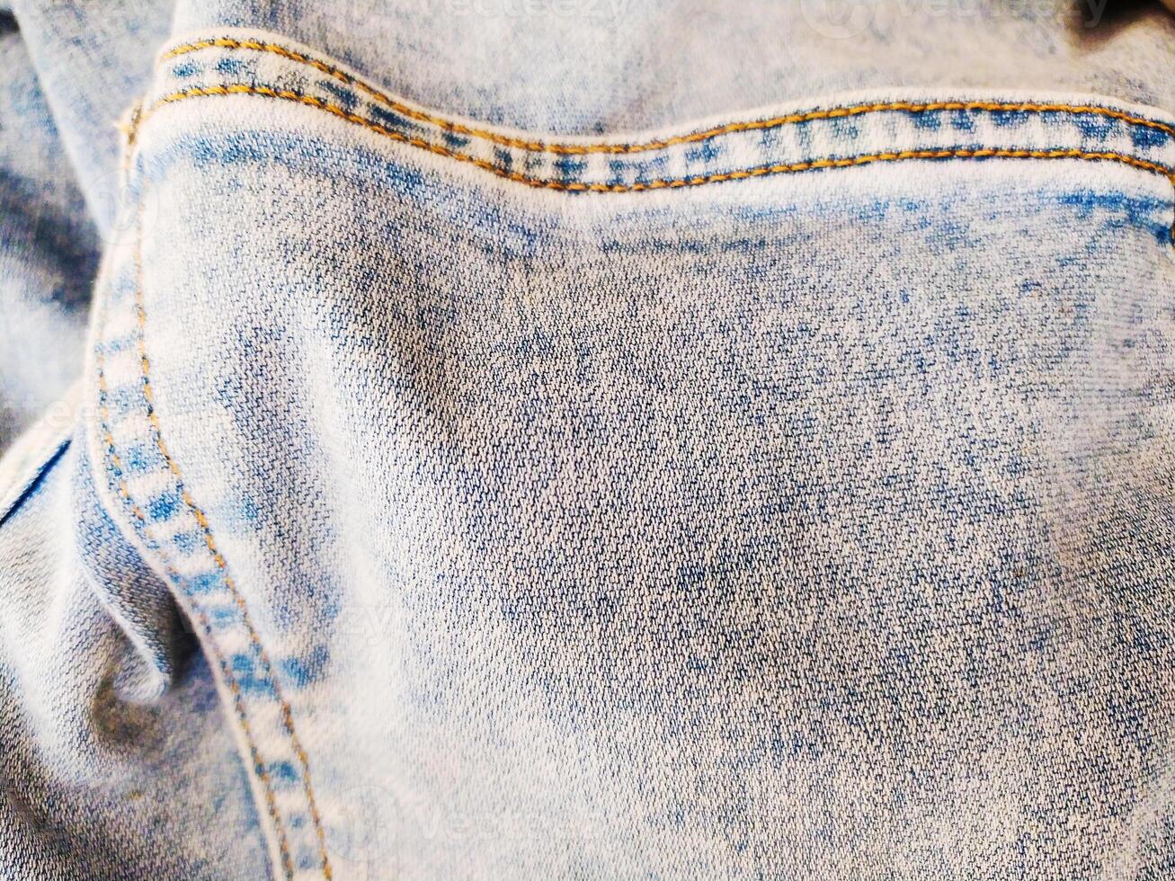 Detailed closeup of worn, lightwash denim fabric. The texture and stitching details are highlighted, ideal for backgrounds, textiles, or fashionrelated concepts. photo