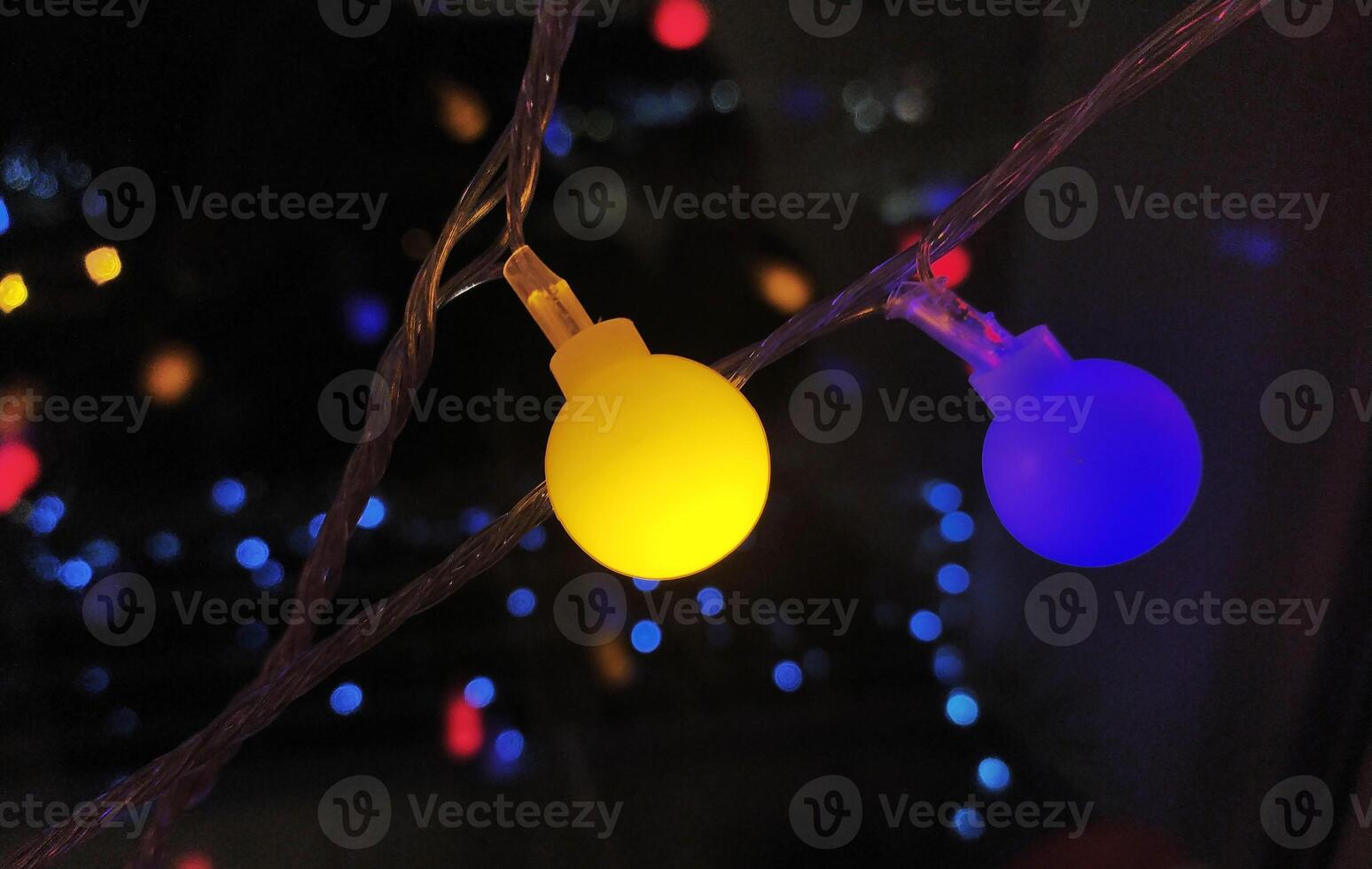 Close-up of vibrant yellow and blue LED lights on a string, creating a festive and modern bokeh effect against a dark background. photo