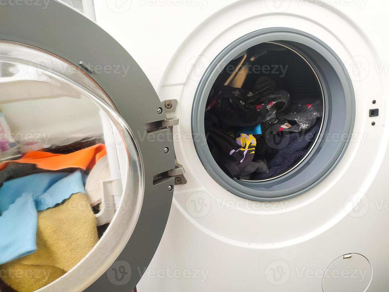 Open washing machine filled with colorful clothes. Laundry day concept. Cleaning, household chores, and routine. Use for lifestyle, home, or hygiene topics. photo