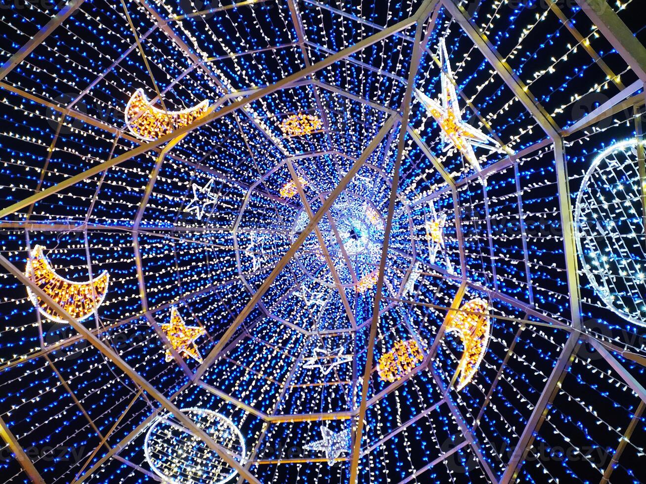 Stunning low-angle view of a dazzling light installation featuring stars and moons. Perfect for holiday, celebration, or whimsical designs. photo