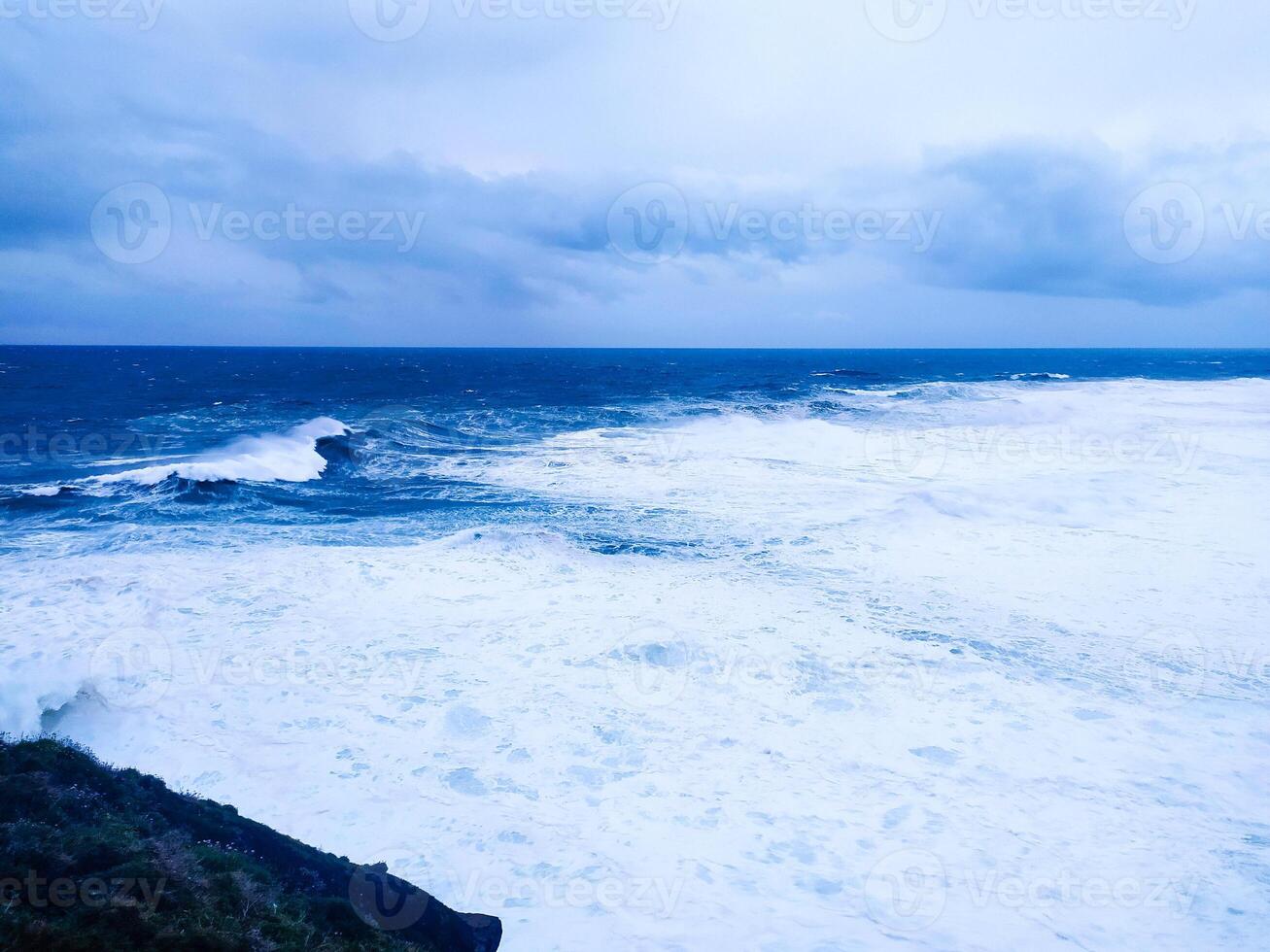Dramatic ocean landscape featuring turbulent waves under a moody sky. Evokes themes of power, nature, and unpredictability. Ideal for conveying strength and resilience. photo