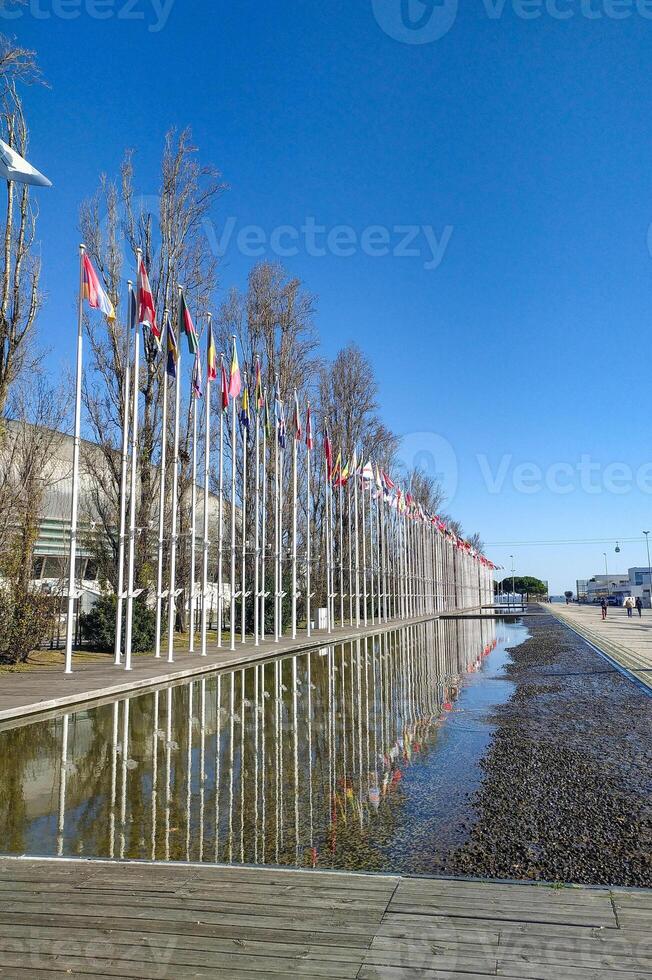 Serene outdoor scene featuring numerous flags reflected in a tranquil water feature. Perfect for themes of international cooperation, global events, or peaceful gatherings. photo
