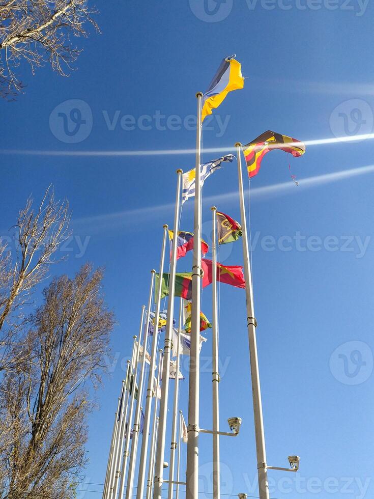 Vibrant international flags wave against a clear blue sky. A perfect image for concepts of global unity, diversity, travel, or international events. photo