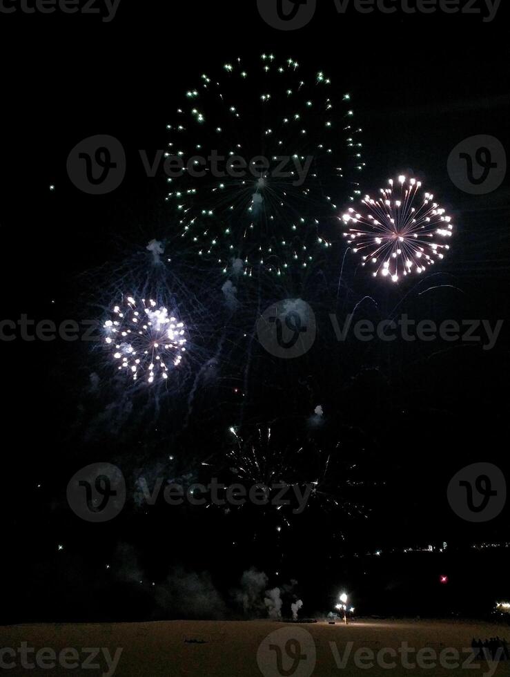 Stunning fireworks display illuminating the night sky. Multiple bursts of vibrant colors create a captivating spectacle perfect for celebrations, holidays, or event promotions. photo