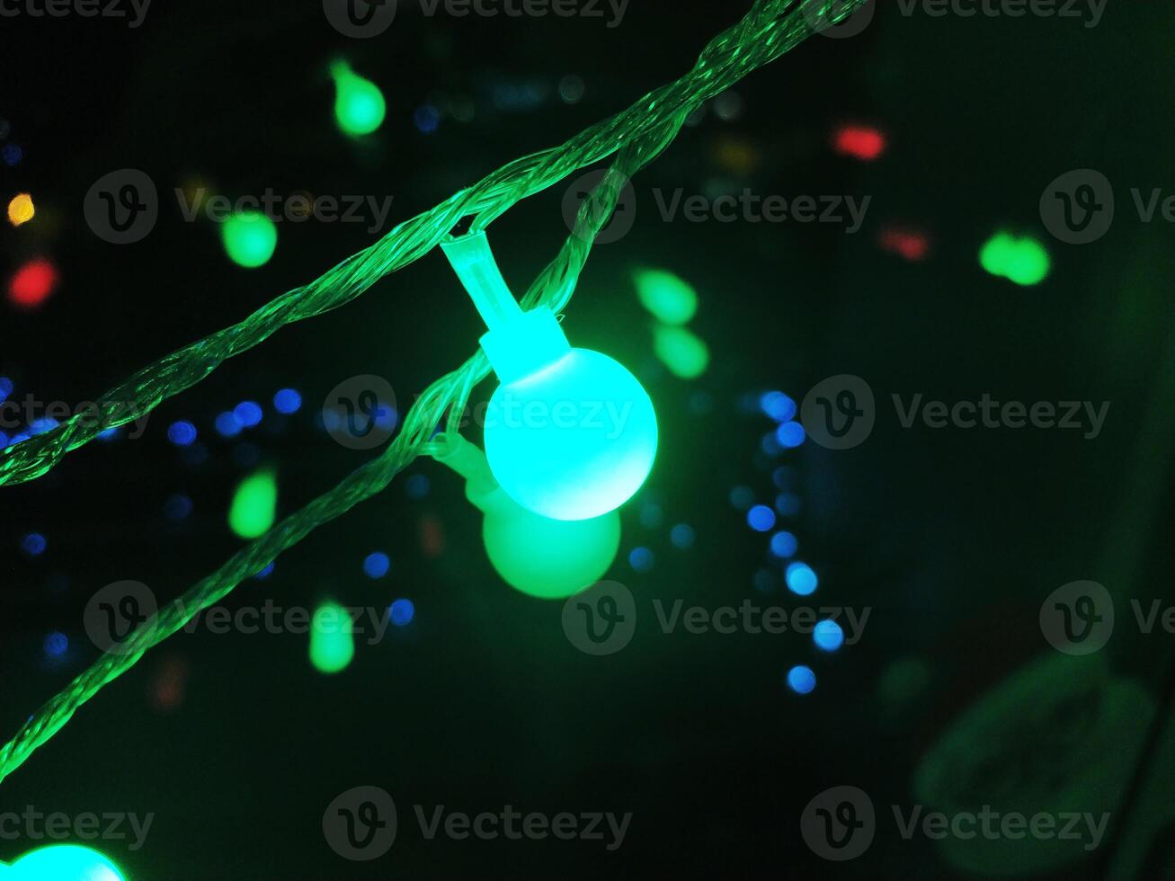 Vibrant teal and green fairy lights illuminate the dark background, creating a magical and festive atmosphere. photo