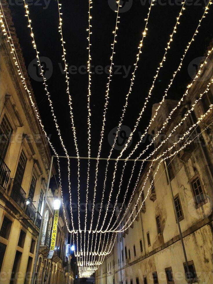 Romantic nighttime street scene. Warm fairy lights strung overhead create a magical ambiance in a historic, European-style alleyway. Perfect for travel, holiday, or romance themes. photo