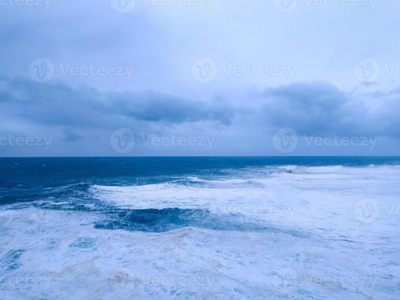 Dramatic seascape featuring turbulent waves under a moody, overcast sky. Evokes raw power, isolation, and the beauty of nature. Perfect for weather, travel, or environmental concepts. photo
