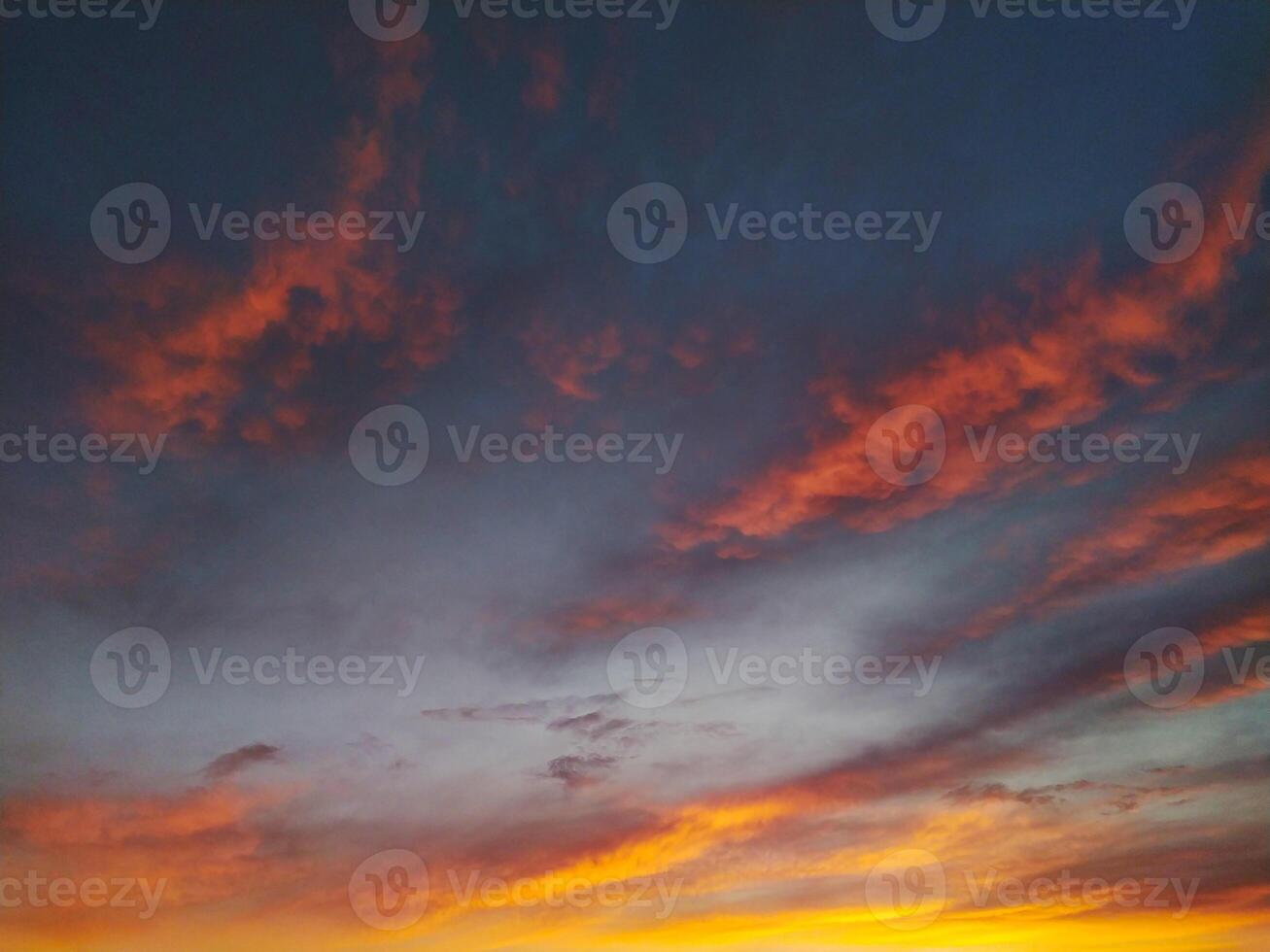 Dramatic sunset sky with vibrant orange and pink clouds against a dark grey backdrop. Perfect for backgrounds, travel, or naturethemed projects. Evokes feelings of serenity and awe. photo