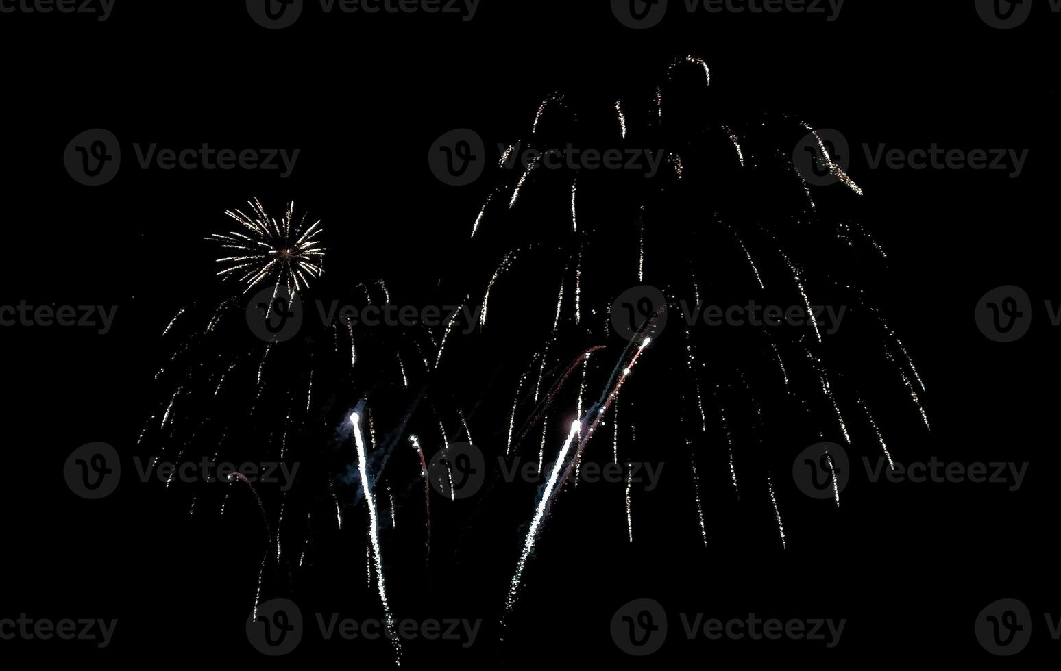 Stunning fireworks display against a deep black night sky. Silver and white sparks illuminate the darkness, creating a dramatic and celebratory scene. photo
