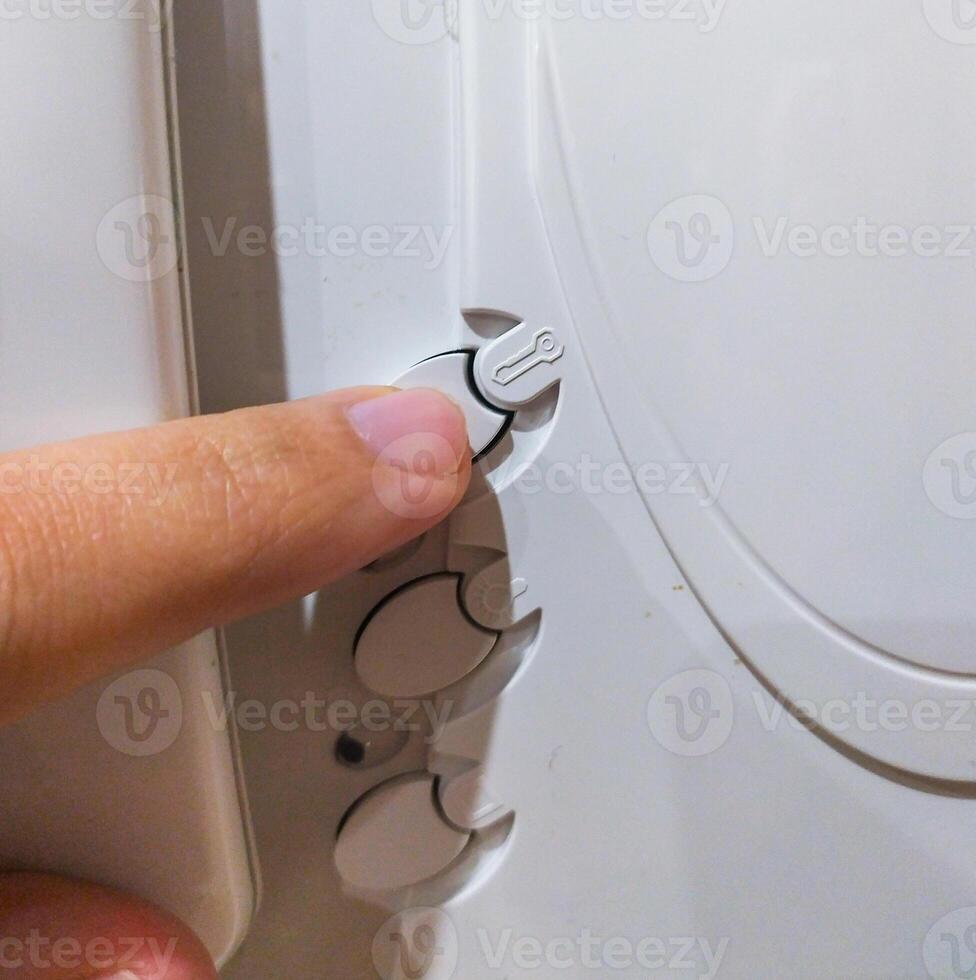 Closeup shot focusing on a finger adjusting settings or controls on a white device. Symbol of precision, technology, or domestic appliances. Usable for service or assistance concepts. photo