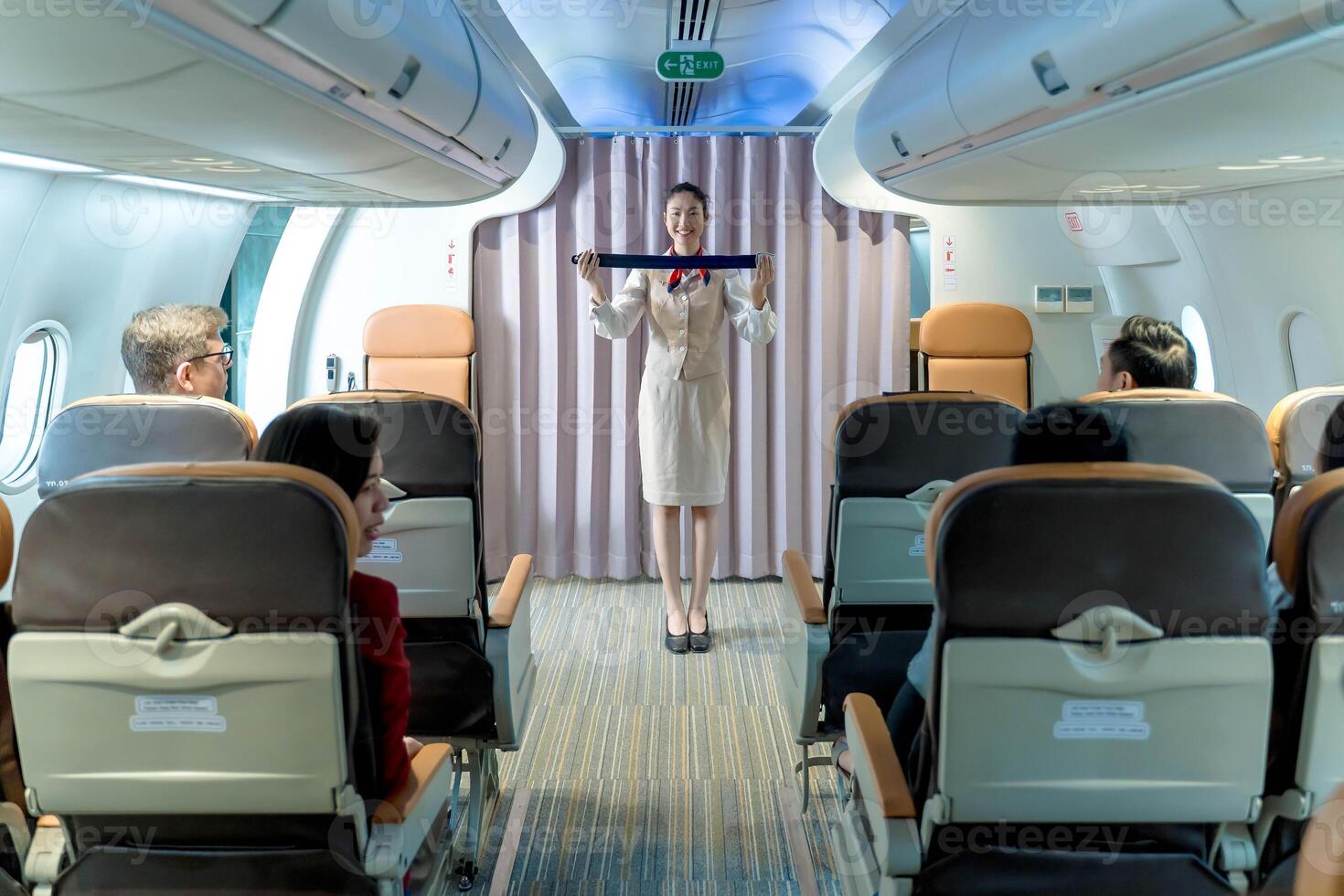 Flight attendant demonstrating seatbelt instructions to passengers inside an aircraft cabin during pre-flight safety briefing for airline travel safety awareness photo