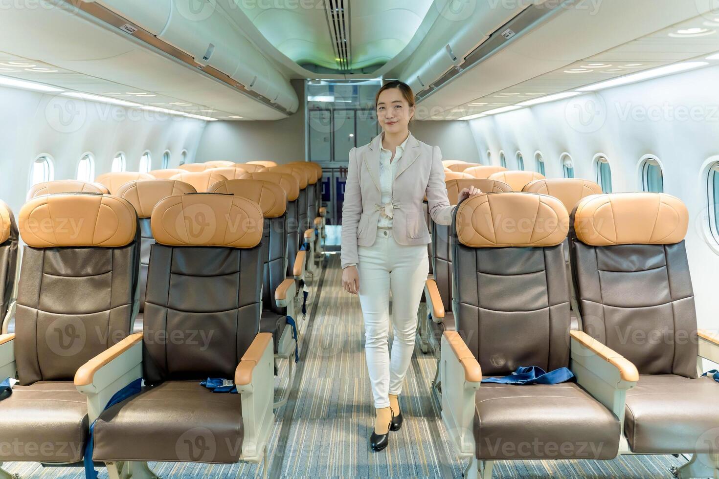 Stylish businesswoman confidently walking down airplane aisle, showcasing air travel lifestyle and modern fashion in a bright, empty commercial aircraft cabin photo