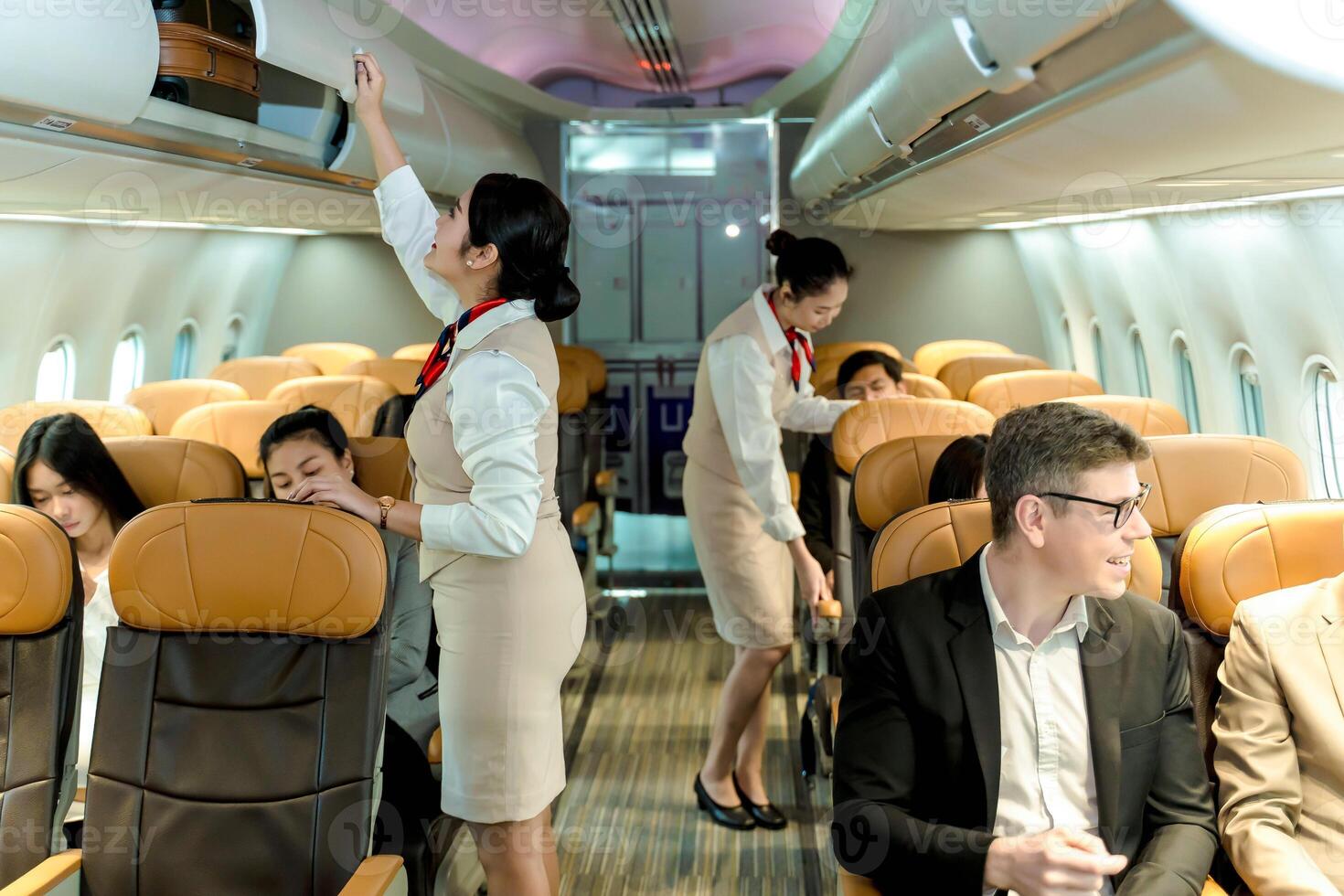 Cabin crew assisting passengers and securing overhead luggage during commercial flight, ensuring safety and comfort in modern airplane cabin environment photo