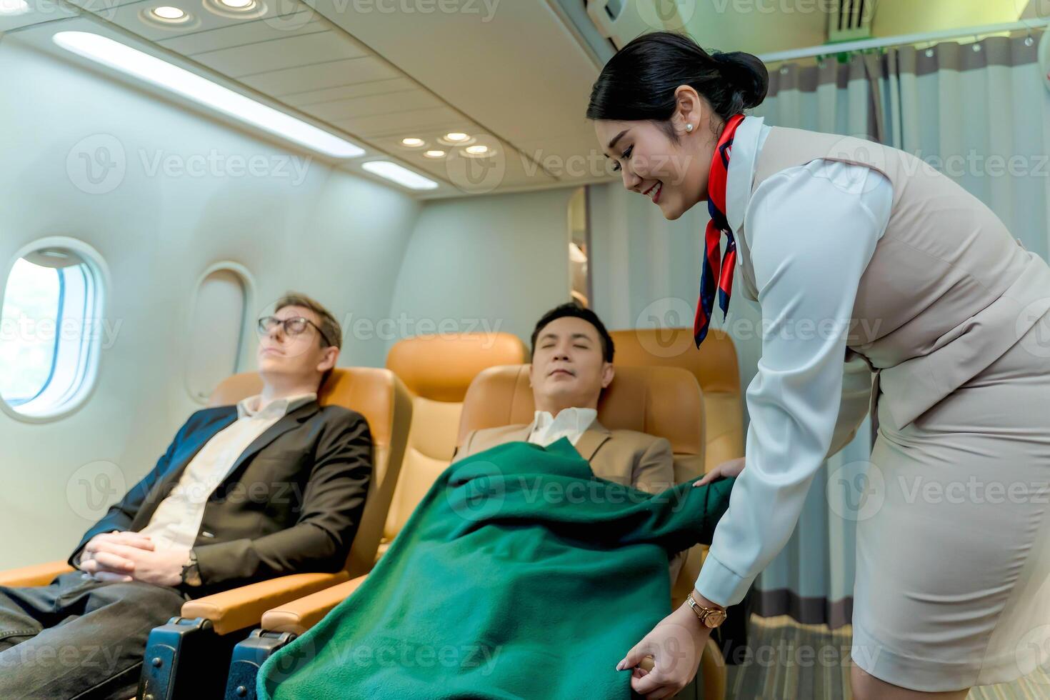 Flight attendant offering blanket to resting business class passenger during flight, highlighting care, comfort, and premium in-flight service experience photo
