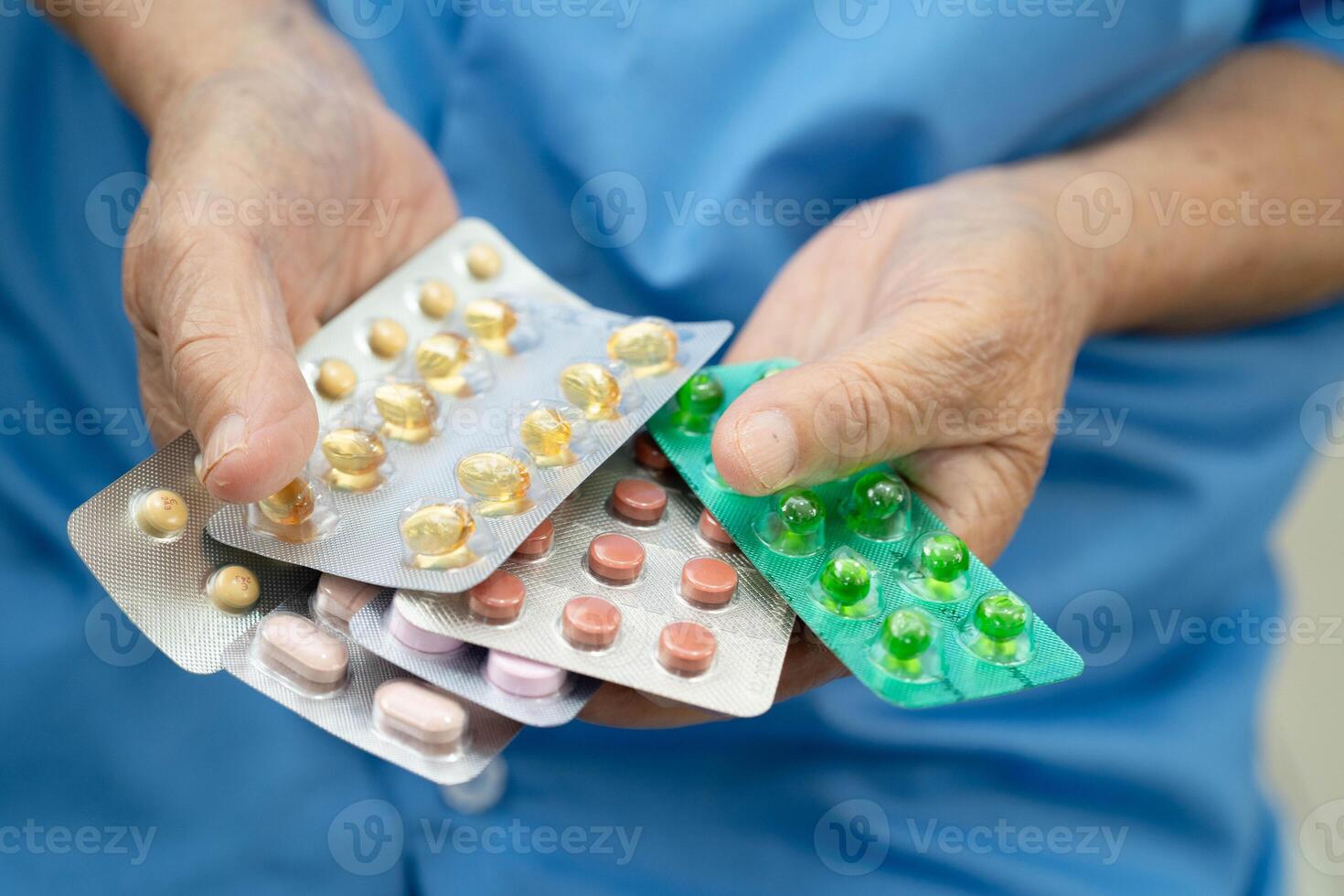 Asian elderly woman holding pill drug in hand, strong healthy medica photo