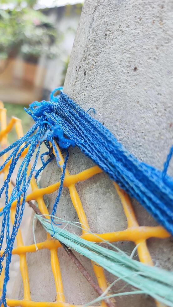 A blue rope tied to a yellow pole photo