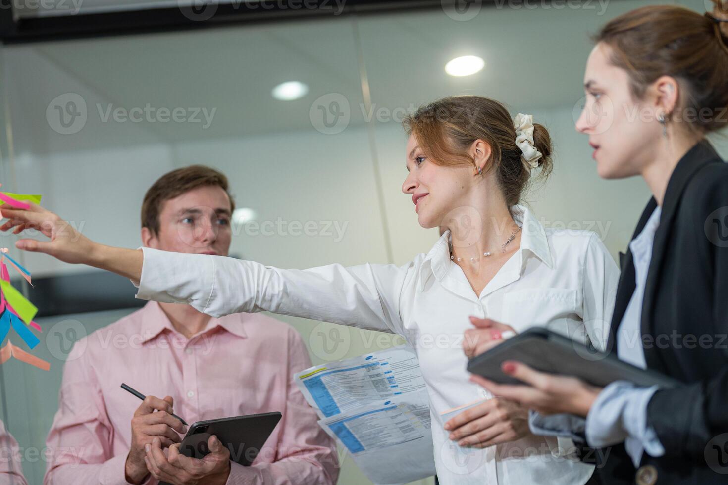 Business team collaborates in office to develop project ideas with sticky notes during a meeting in the early afternoon photo