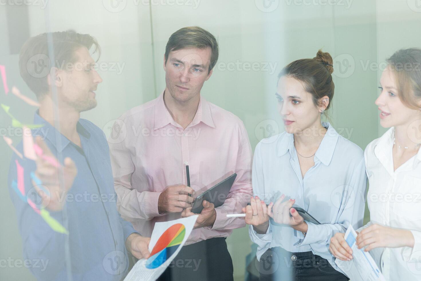 Team members collaborate in a modern office during a strategy meeting while analyzing data on charts and reports photo