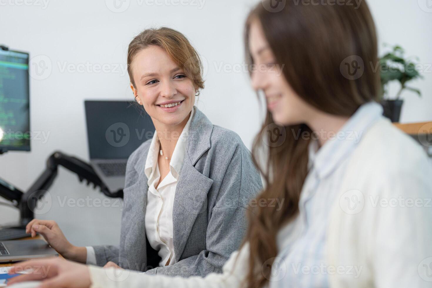 Two women collaborating in a modern office environment while discussing a project during the afternoon photo