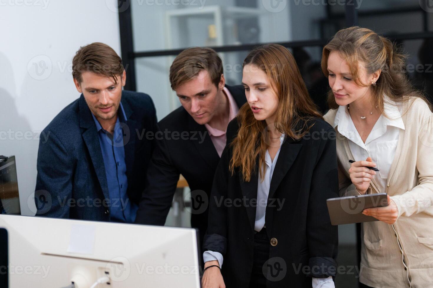 Team collaborates on project while reviewing data on computer screen in a modern office setting photo