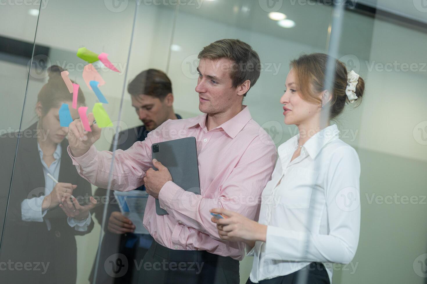 Team collaborates in modern workspace while discussing project using sticky notes and a digital device photo