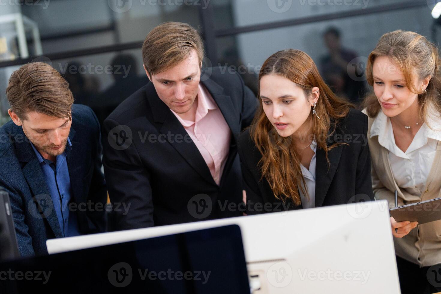 Team collaboration during a business meeting in a modern office setting with individuals focused on a computer screen photo