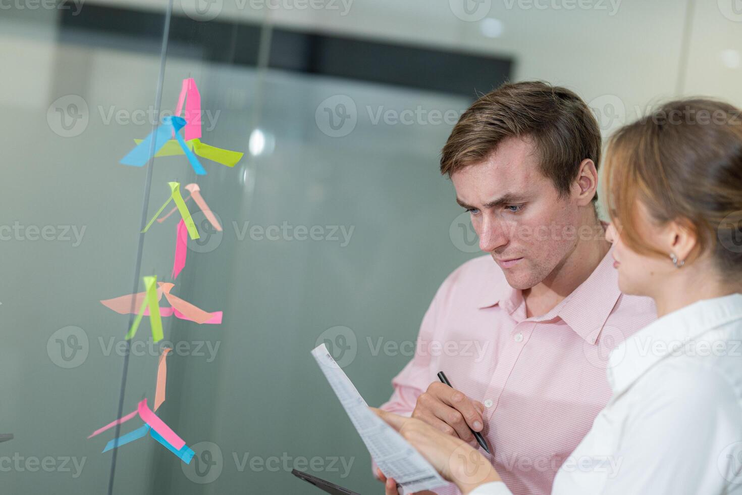 Team members collaborate on project planning with sticky notes in modern office setting in the late afternoon photo