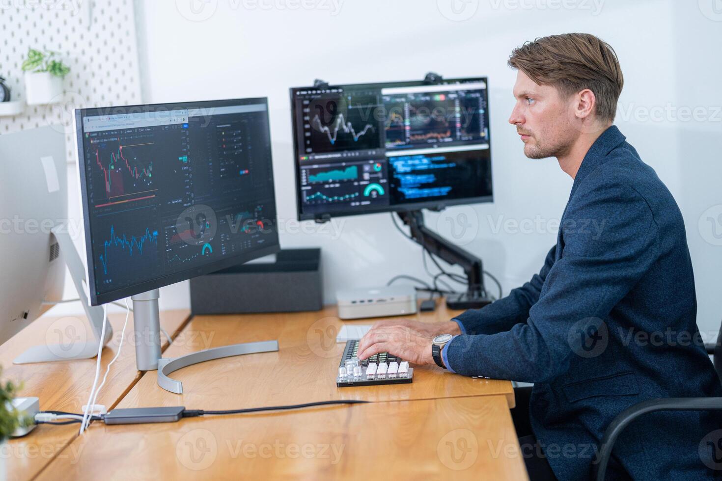 Professional trader analyzing financial data at his desk with multiple monitors displaying stock market trends photo