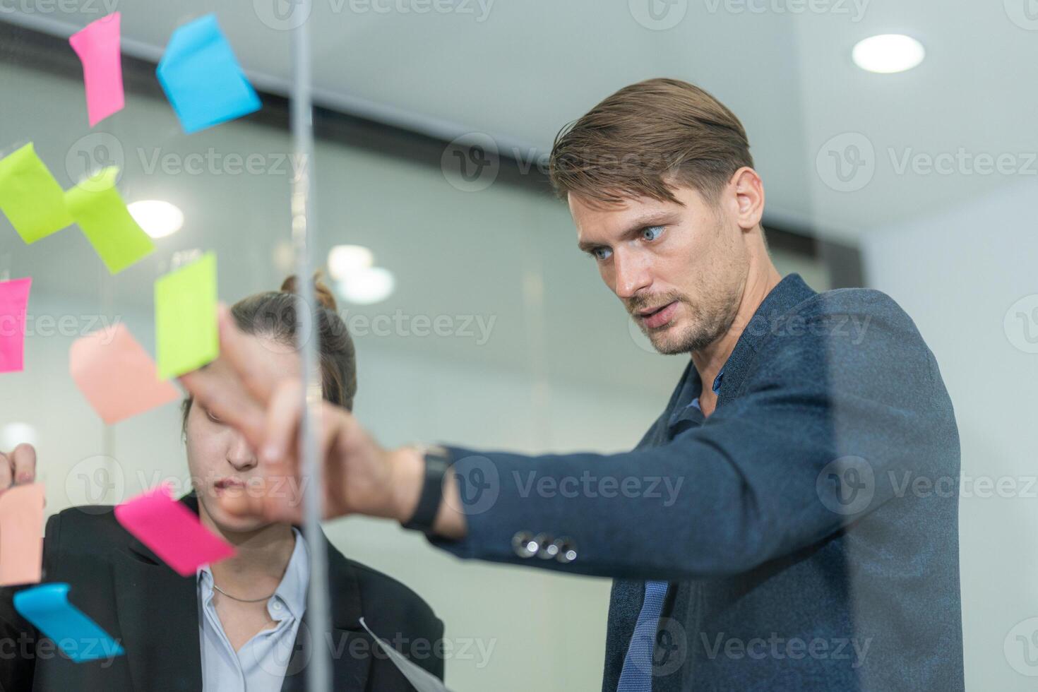 Collaboration at an office brainstorming session with sticky notes on glass wall photo