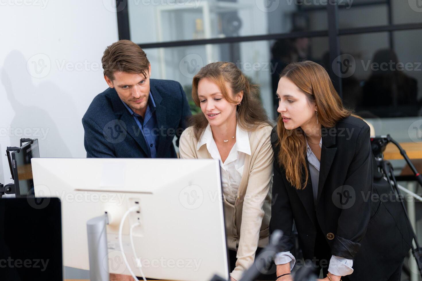 Team collaborates in modern office while analyzing data on computer screen during business meeting photo