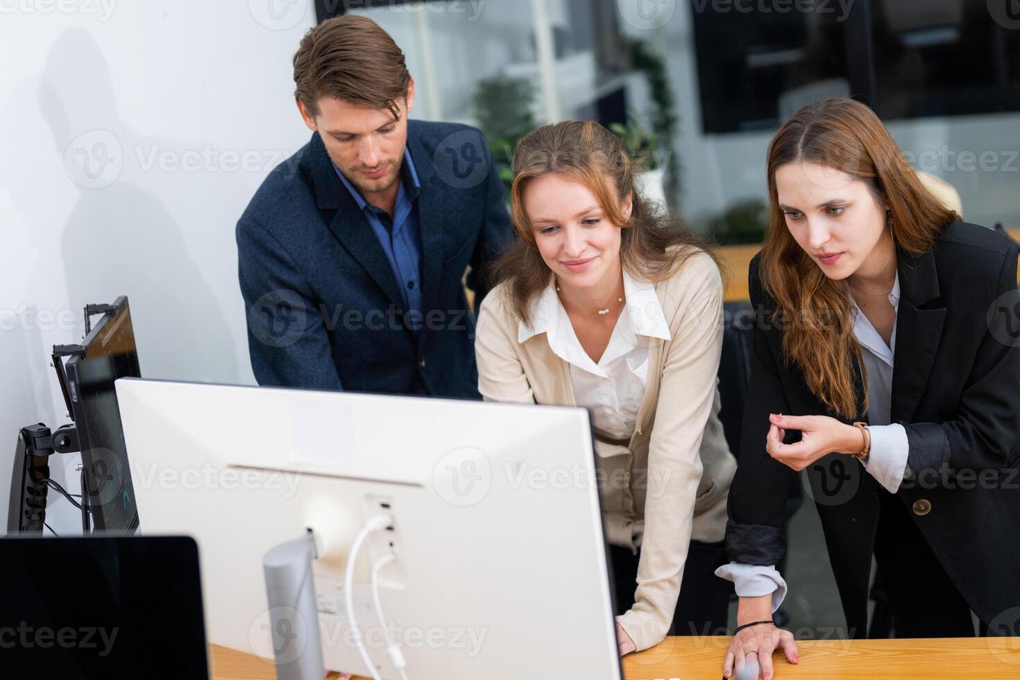 Professionals collaborating in modern office, analyzing data on computer screen, emphasizing teamwork and innovation photo