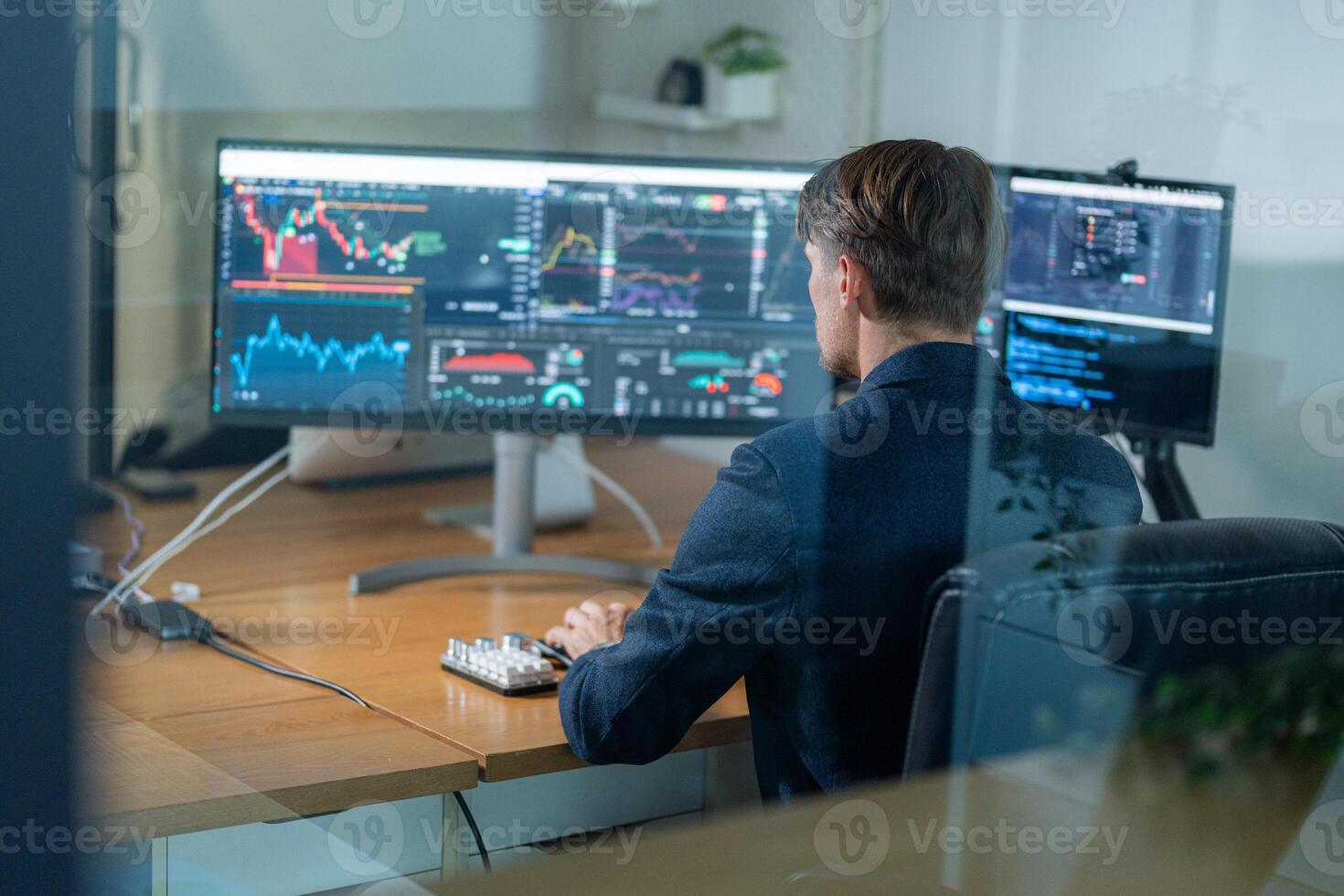 Financial analyst monitoring market trends using multiple displays in a modern office during business hours photo
