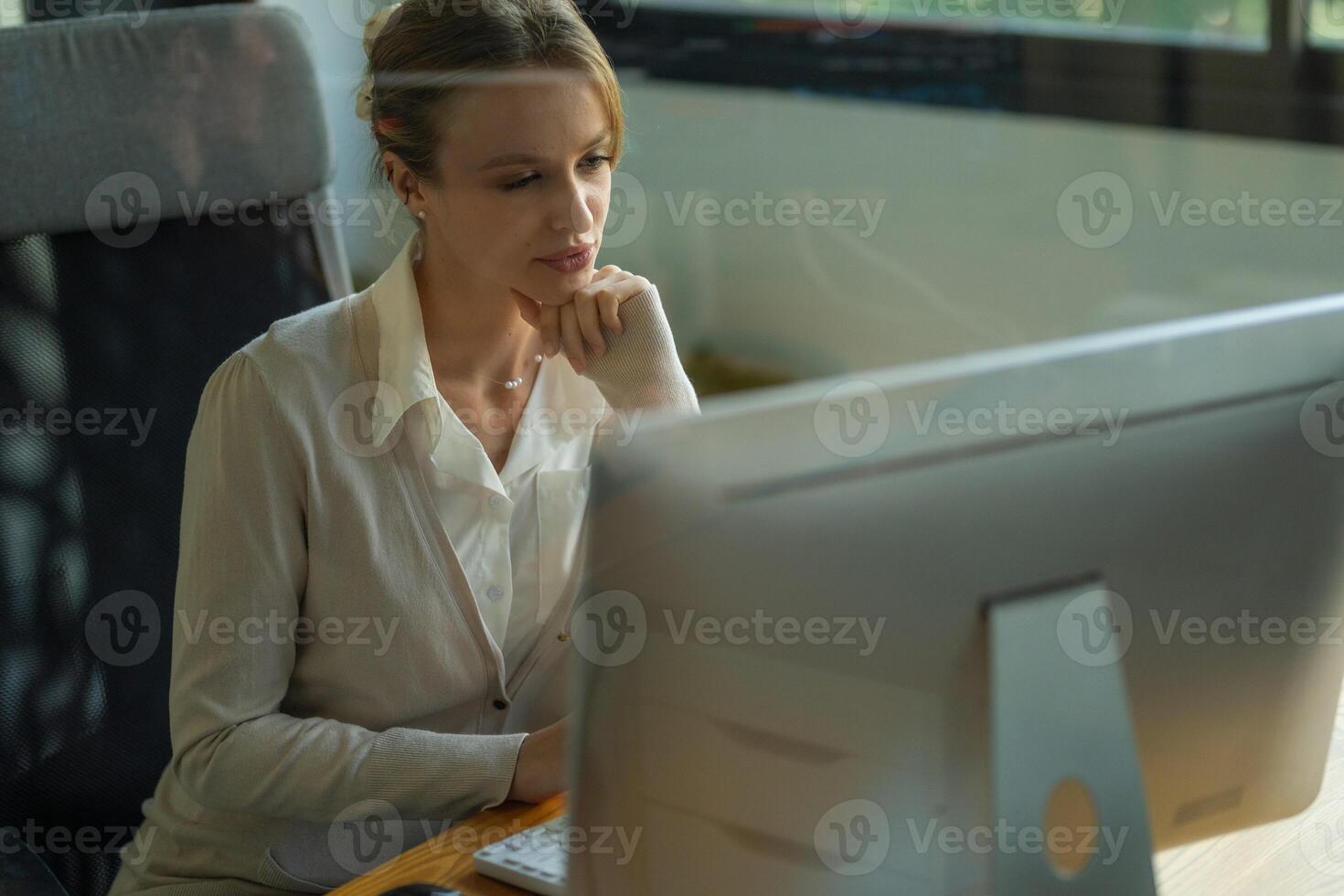 Professional woman deep in thought while working on a computer in a modern office setting during the daytime photo