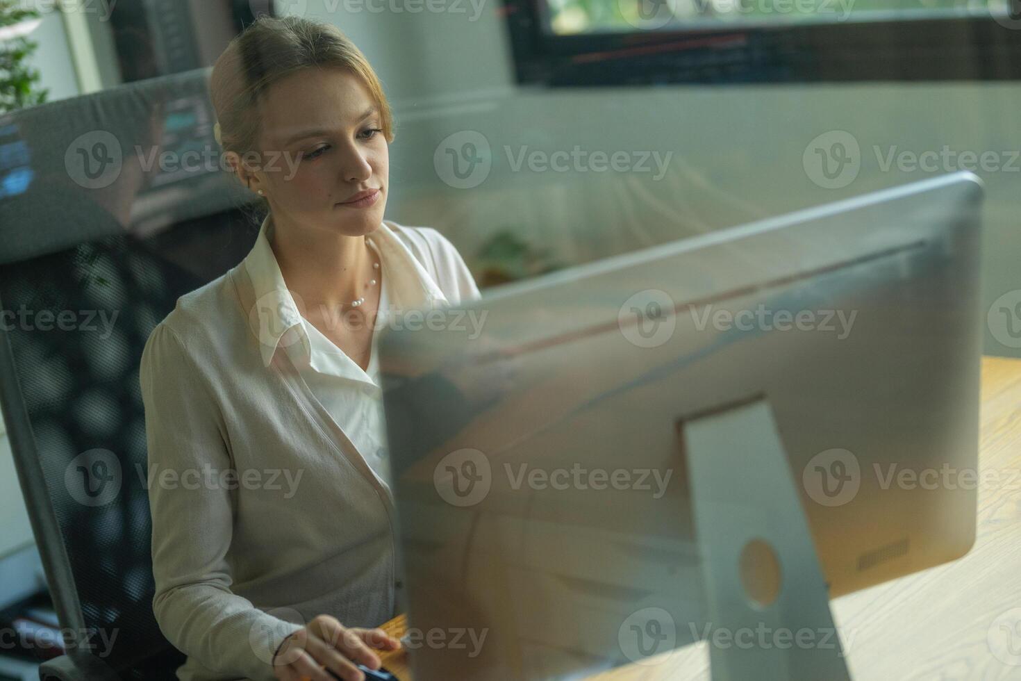 Professional woman working at a computer in a modern office environment during the day photo