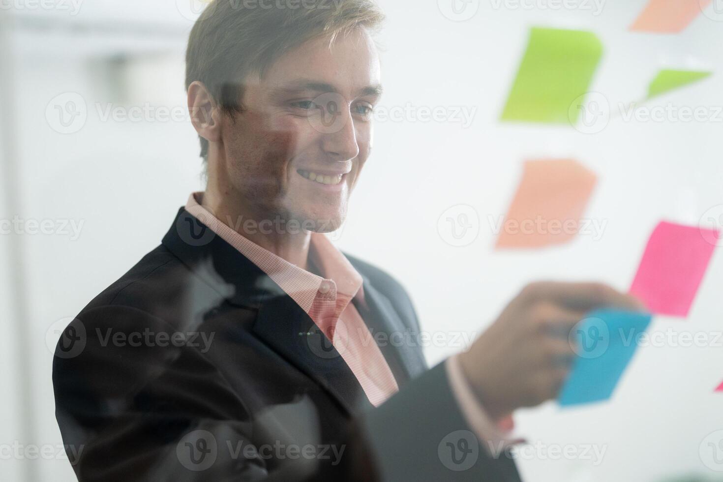 Business professional engages in brainstorming session with colorful sticky notes at an office photo